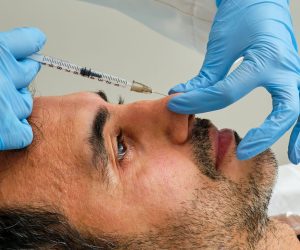 dark-haired man undergoing cosmetic treatment on his nose with botulinum toxin